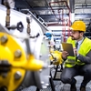 Man wearing a hard hat looking at a device in the field
